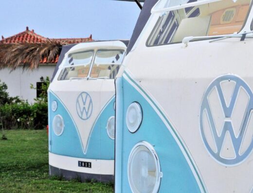 Two vw camper vans are parked in front of a house.