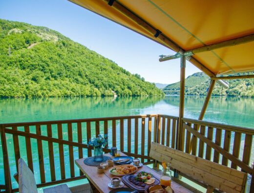 A wooden table and chairs on a deck overlooking a lake.
