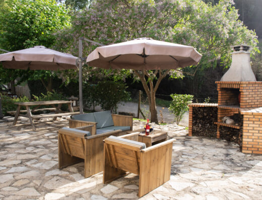 A brick patio with a grill and umbrellas.