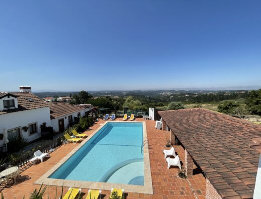 A swimming pool with lounge chairs and a view of the countryside.