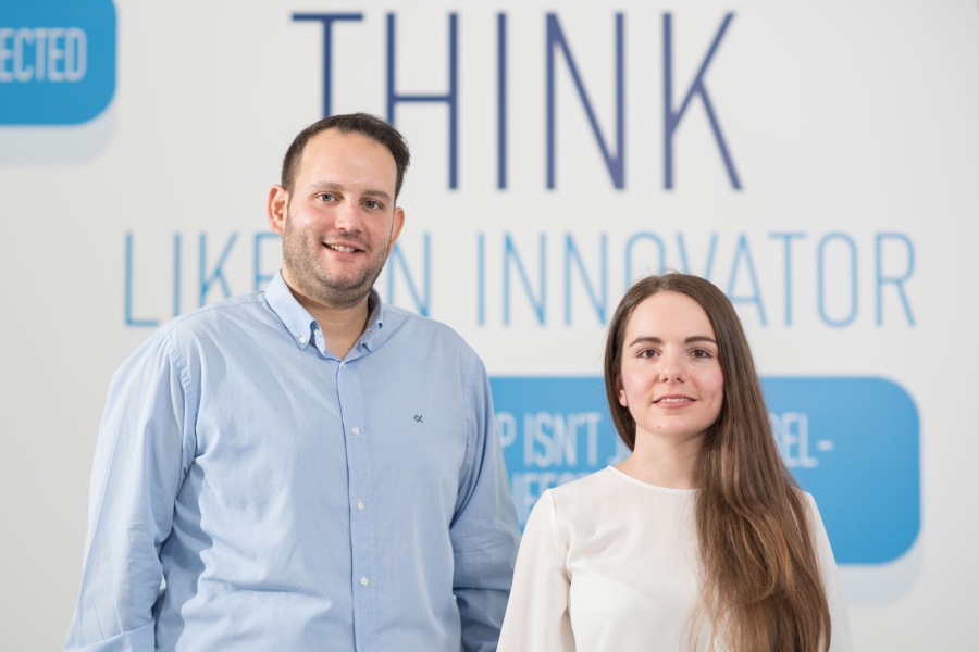 Two people standing in front of a Think Like an Innovator sign, celebrating their achievement as recipients of the Capsulet Award in 2020.