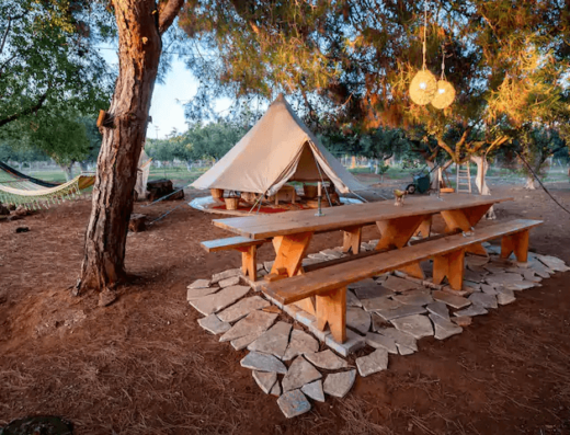 A tent and picnic table in a wooded area.