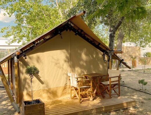 A tan tent with a wooden table and chairs.