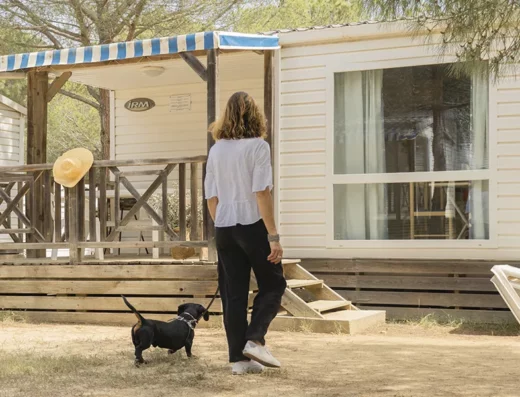 A woman walking her dog in front of a mobile home.