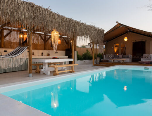 A swimming pool with lounge chairs and a teepee.