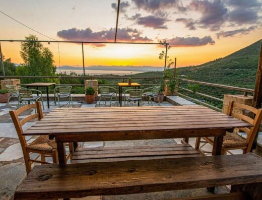 A wooden table and chairs with a view of the mountains at sunset.