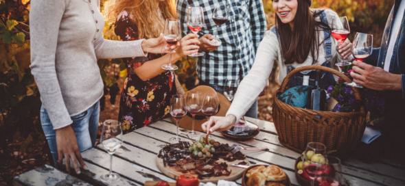 Exploring the Riches of Wine Tourism in Greece, a group of friends enjoy their favorite wines while seated at a picnic table.