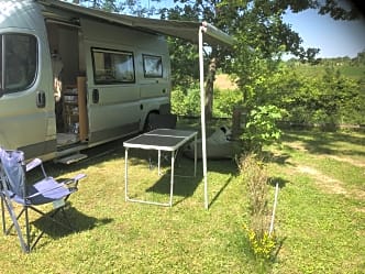 A camper van and a table in a grassy area.