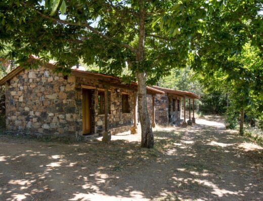 A small stone cabin surrounded by trees.