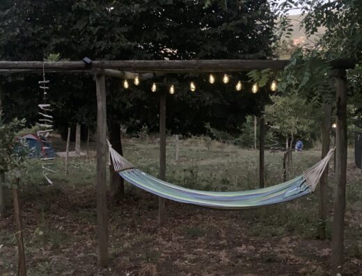 A hammock in a wooden frame with lights hanging from it.