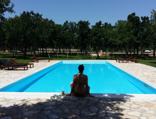 A woman sitting next to a swimming pool.