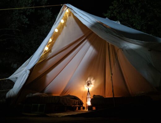 A tent is lit up at night with candles.