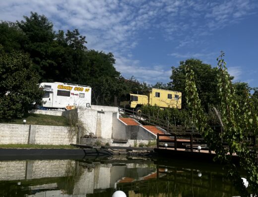 A yellow rv parked next to a pond.