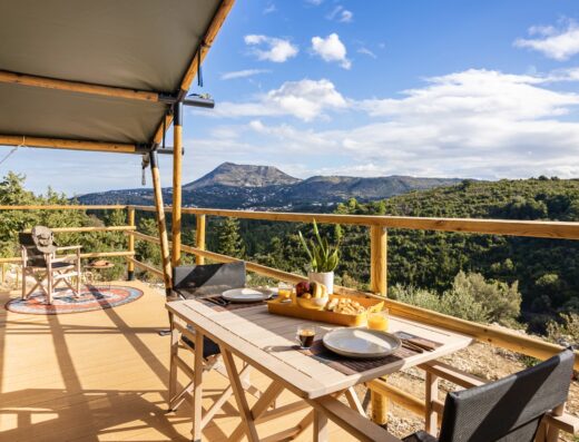 A wooden deck with a table and chairs overlooking the mountains.