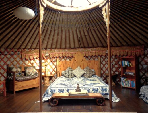 A yurt with a bed and a bedside table.