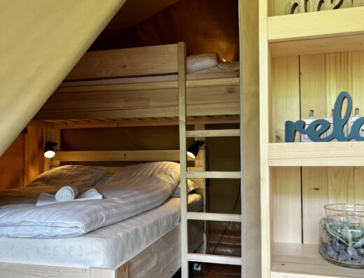 A tent with a bed and a shelf in it.