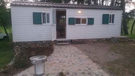 A small white cabin with green shutters in the woods.