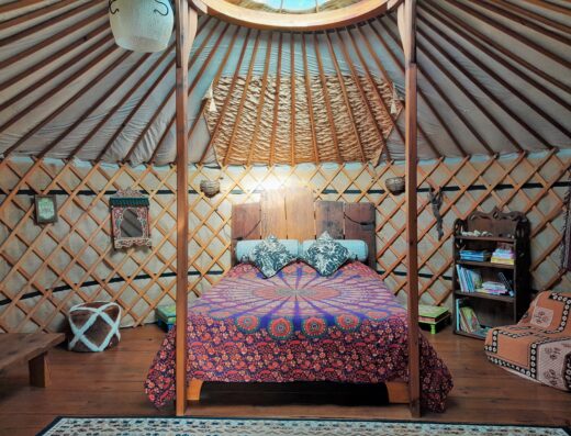 A yurt with a bed and a bedside table.