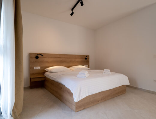 Minimalist and tidy bedroom with a wooden bed and white bedding.